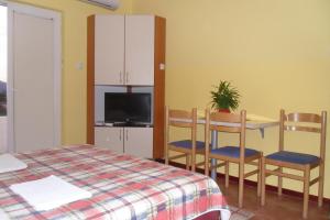 a bedroom with a table and chairs and a tv at Apartments Marović in Luštica