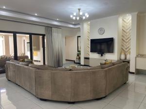 una gran sala de estar con un gran sofá marrón en The House en Hazyview