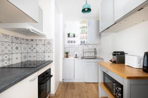 a white kitchen with white cabinets and wooden floors at Charming and Natural T2 neuf - Hyper-centre Meaux - Disneyland Paris in Meaux