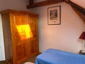 ein Schlafzimmer mit einem Holzschrank und einem Bett in der Unterkunft Le logis de l'Epte in Saint-Clair-sur-Epte