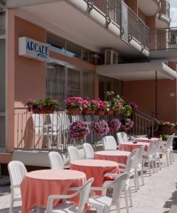 una fila de mesas y sillas blancas frente a un edificio en Hotel Arcade, en Rímini