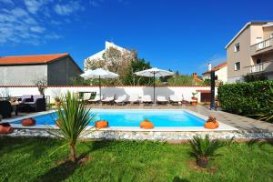 a swimming pool in a yard with chairs and umbrellas at Villa Vanilla with Heated Pool in Zadar