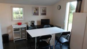 uma cozinha com uma mesa e cadeiras brancas e uma janela em Gîte Les Tilleuls em Beurlay