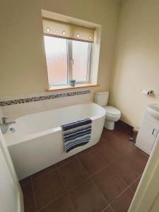 uma casa de banho com uma banheira, um WC e uma janela. em The Bays em Bridlington