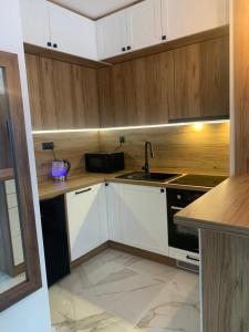 a kitchen with white cabinets and a sink and a stove at Apartament Fordon przy Onkologii in Bydgoszcz
