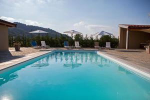 a blue swimming pool with chairs and mountains in the background at Agriturismo Casa Matilde in Lauriano