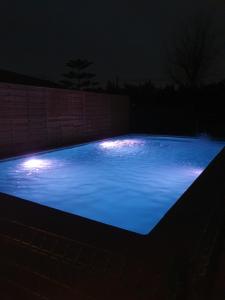 uma piscina com água azul à noite em CHalet aeropuerto Sevilla em Sevilha