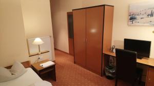 a hotel room with a bed and a desk and a cabinet at ParkHotel Nieheim in Nieheim