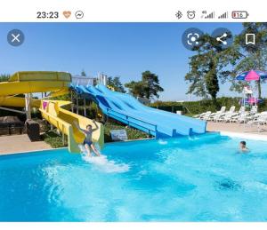 a slide in a swimming pool with two people in it at Assist Mobil home 328 - Mobil Home élégance 3 chambres 6 couchages in Onzain
