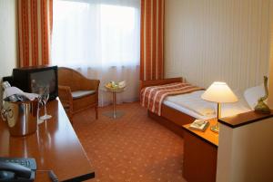 a hotel room with a bed and a chair and a television at ParkHotel Nieheim in Nieheim