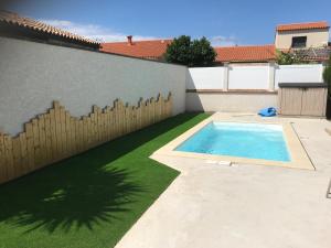 a backyard with a swimming pool and a fence at Gîte de Leni - Maison avec piscine in Torreilles