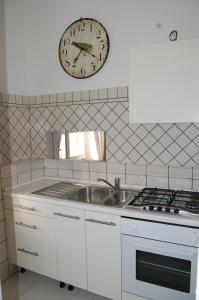 eine Küche mit einem Waschbecken und einer Uhr an der Wand in der Unterkunft SeaBaudia 2 SENZA TERRAZZA in Sabaudia