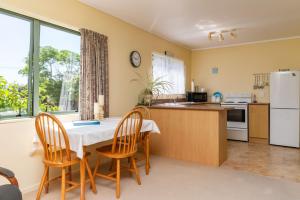 a kitchen with a table and chairs and a refrigerator at Hibiscus House - Mangawhai Heads Holiday Home in Mangawhai