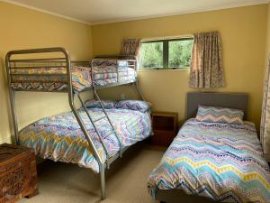 a bedroom with two bunk beds and a window at Hibiscus House - Mangawhai Heads Holiday Home in Mangawhai