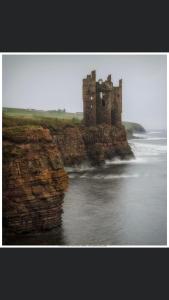 un castello sul bordo di un corpo d'acqua di Sinclair Bay Apartments a Keiss