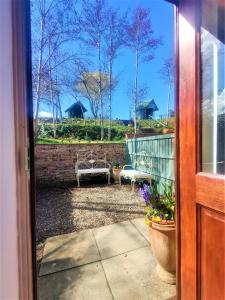 a door leading to a patio with a bench in a yard at Curlew's Nest in Ruthin