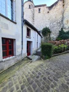 uma rua de calçada em frente a um edifício com portas vermelhas em Les Logis du rempart em Loches