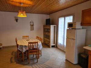 a kitchen and dining room with a table and a refrigerator at Maison De Vacances in Saint-Denis-dʼOléron