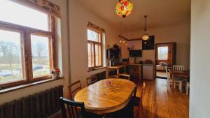 a kitchen and dining room with a wooden table and windows at Butterfly House in Pāvilosta