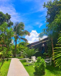 a yard with chairs and palm trees and a house at Pipa Style in Pipa