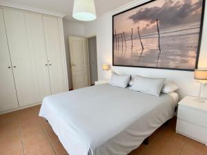 a white bed in a bedroom with a painting on the wall at Apartamento en Playa de la Tejita, El Medano in Granadilla de Abona