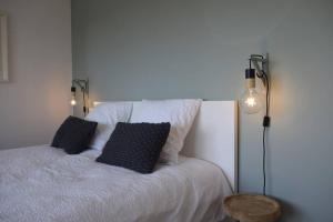 a bedroom with a white bed with two black pillows at Gîte le 44 - au calme avec jardin, proche de Namur in Namur