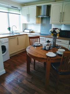 uma cozinha com uma mesa de madeira com cadeiras e um lavatório em lovely 1 bedroom borders cottage em Town Yetholm