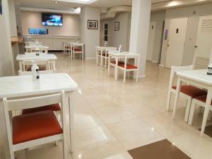 un comedor con mesas blancas y sillas blancas en Hotel C&R en Mar del Plata