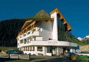 ein großes Gebäude mit einem davor geparkt in der Unterkunft Hotel Casada - inklusive Sommer Card in Galtür