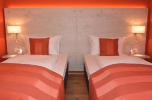 two beds in a hotel room with two lamps at Hotel Schlee in Hohenschäftlarn