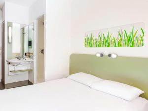 a white bedroom with a bed and a sink at ibis budget London Hounslow in Hounslow