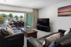 een woonkamer met een bank, een televisie en een tafel bij Luxury Waterfront Apartment - Abode No 1 in Picton