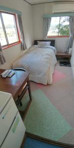 a bedroom with a bed and a table and windows at 田舎の宿 吉田屋 in Ōgo