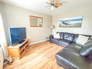 a living room with a leather couch and a flat screen tv at Portrush Getaway - Holiday Let in Portrush
