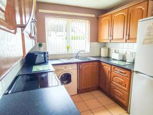 a kitchen with wooden cabinets and a washer and dryer at Portrush Getaway - Holiday Let in Portrush