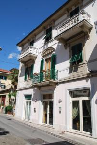a white building with green shutters on a street at Hotel Conchiglia in Montecatini Terme