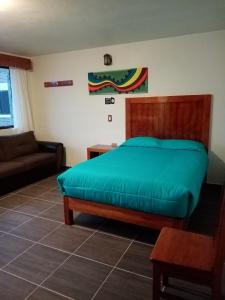 a bedroom with a green bed and a couch at Hotel Tlatoani in Chignahuapan