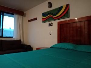a bedroom with a green bed and a chair and a window at Hotel Tlatoani in Chignahuapan