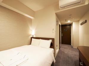 a hotel room with a bed with white sheets at Sotetsu Fresa Inn Tokyo Roppongi in Tokyo