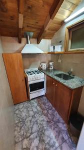 uma cozinha com um fogão e um lavatório em Casita Fontanive em San Martín de los Andes