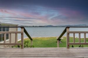 タウランガにあるStay Coastal - Tauranga Beach Houseのベンチ2台付きの桟橋から水辺の景色を望めます。