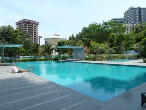 a person sitting on the edge of a swimming pool at KL TOWER & KLCC VIEW HOTEL SUITE @ SUASANA BUKIT CEYLON BUKIT BINTANG in Kuala Lumpur