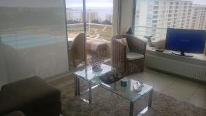 a living room with a couch and a table and a tv at Departamento Laguna Bahia, Algarrobo in Algarrobo