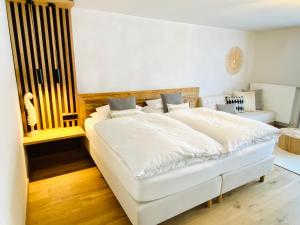 a bedroom with a white bed with a wooden headboard at Verweilzeit Appartementhaus in Ramsau am Dachstein