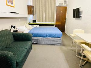 a room with a bed and a couch and a table at Millers Cottage Motel in Wangaratta