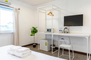 a white room with a desk and a tv at Parasol Inn Chiang Mai Old City Hotel - SHA Plus in Chiang Mai