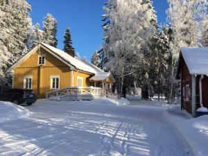 a yellow house in the snow with a snow covered yard at Ollilan tupa Joensuun lähellä in Ylämylly