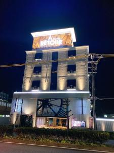een wit gebouw met een neonbord erop bij ルトゥール姫路 Retur HIMEJI 男塾ホテルグループ in Himeji