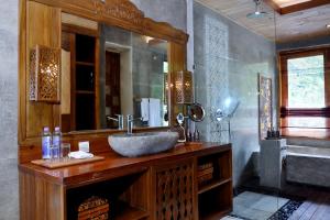 a bathroom with a sink and a large mirror at Kenran Resort Ubud By Soscomma in Ubud