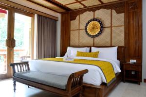a bedroom with a large bed with a yellow blanket at Kenran Resort Ubud By Soscomma in Ubud
